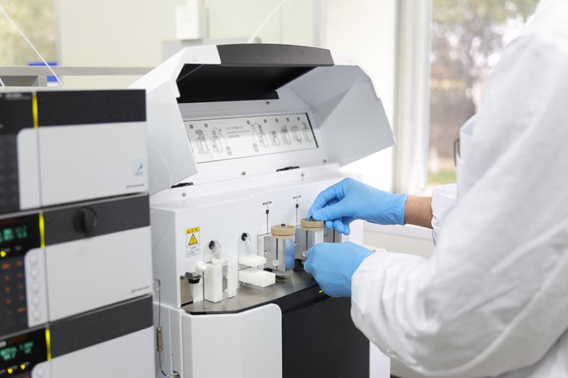 peptides-products-services-full - LUX PEPTIDES Lab technician in blue gloves loading sample tubes into a benchtop analytical instrument in a clean lab environment.